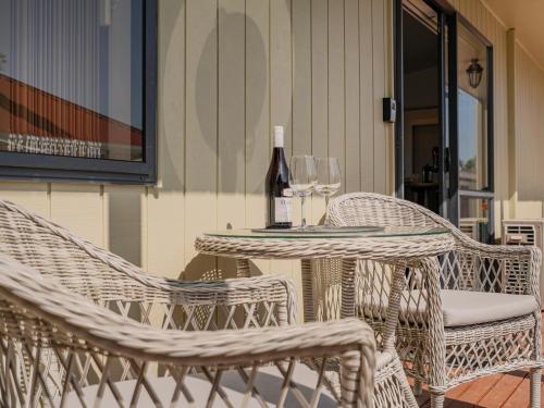 a table with a bottle of wine and two chairs at Gold'n Thames - Thames Holiday Home in Thames
