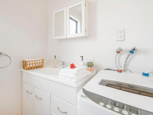 a white bathroom with two sinks and a mirror at Gold'n Thames - Thames Holiday Home in Thames