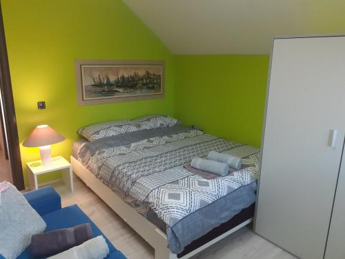 1 dormitorio con paredes verdes, 1 cama y 1 silla en Vidikovac Dedinje, en Šabac