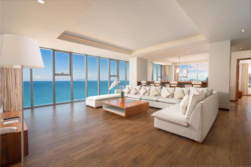 a living room with white furniture and a view of the ocean at A La Carte Da Nang Beach in Danang