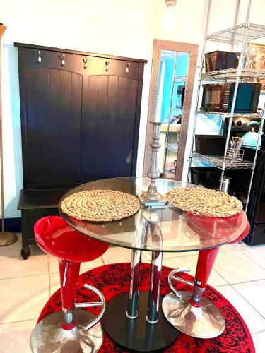 two pizzas sitting on a glass table with red stools at Blue Bell Apartment Hotel in Fort Lauderdale
