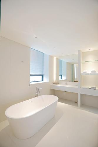 a white bathroom with a tub and a sink at Chengdu Chengshe Hotel - Wenjiang University Town Southwest Caida Branch in Chengdu