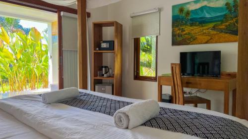 a bedroom with a large bed and a television at Green Valley Lombok in Selong Belanak
