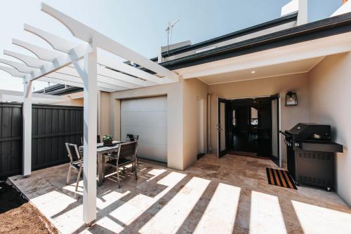 a patio with a white pergola and a table and a grill at McKenna Terraces in Mudgee
