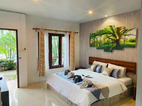 a bedroom with a large bed with a tree painting on the wall at Andawa Lanta Resort in Ko Lanta