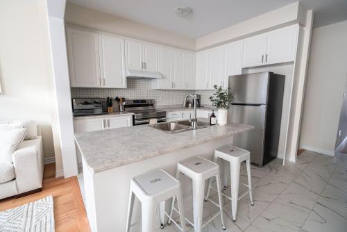 a kitchen with a sink and a refrigerator and stools at BRAND NEW home minutes from Niagara Falls. in Thorold