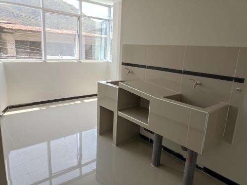 a white bathroom with a sink and a window at Casa Alojamiento Virreynal in San Ramón