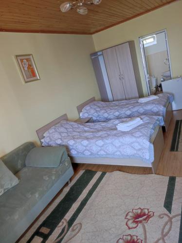 two beds in a room with a couch and a rug at Осенний Иссык Куль in Cholpon-Ata