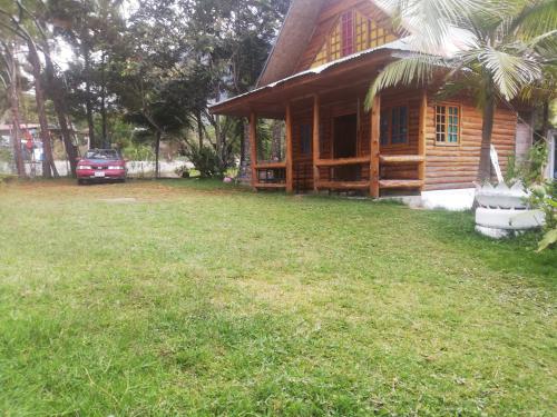 a wooden house with a grass yard in front of it at SHERANPAZ in Oxapampa
