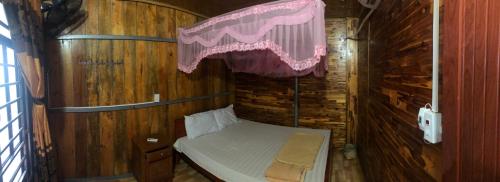 a small room with a bed in a wooden wall at Minh Quang homestay in Ba Be