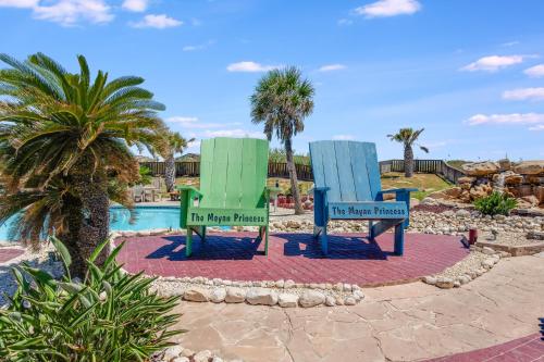 two blue and green chairs in front of a pool at Mayan Princess 101 Beachfront Resort in Port Aransas