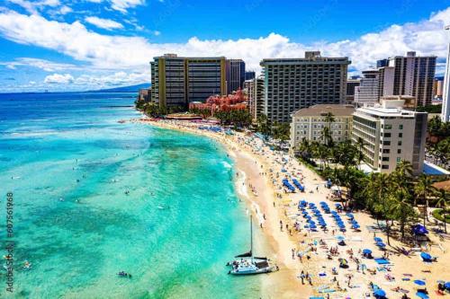 a beach with chairs and people and the ocean at Seashore Waikiki studio 1 block from a beach No Resort Fees in Honolulu