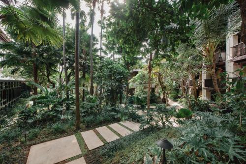 a garden with palm trees and a walkway at Ramayana Suites and Resort in Kuta