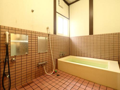 a bathroom with a tub and a sink and a mirror at 民宿 朝富士 in Yamanakako