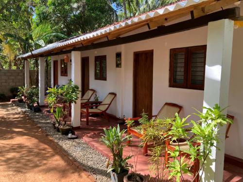 a house with chairs and plants in front of it at Lake House Homestay in Anuradhapura