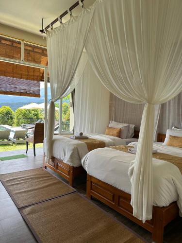 a bedroom with two beds with white drapes at Atres Sari Resort in Munduk