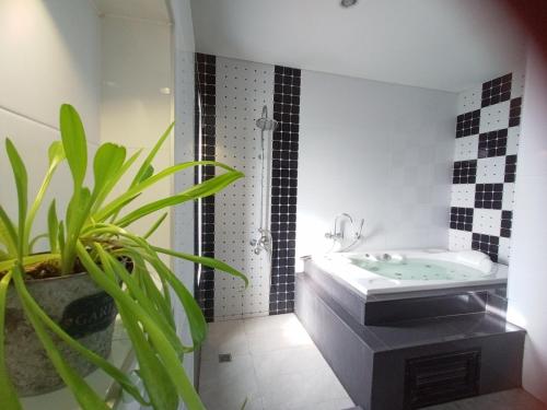 ein Badezimmer mit einer Badewanne und einer Topfpflanze in der Unterkunft Richly's​ Pool​ villa​@Phitsanulok​ in Phitsanulok