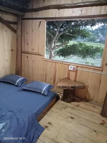 a bedroom with a bed and a window in a cabin at Y BÉ Homestay in Kon Von Kla