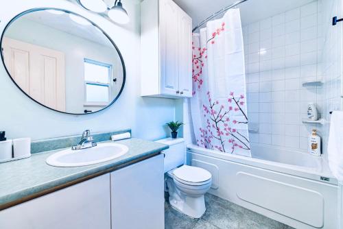 ein Badezimmer mit einem Waschbecken, einem WC und einem Spiegel in der Unterkunft Three-Tree Villa-Central Location in Vancouver