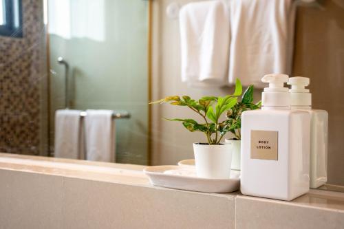 a bathroom counter with a bottle of soap and a plant at Chor Cher The Luxury Green Hotel - SHA Extra Plus in Bang Bo