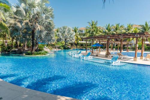 una piscina en un complejo con sillas y palmeras en Villas Aqua Los Cabos, en Monterrico