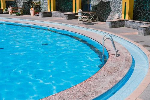 uma piscina com água azul em Kapal Garden Hotel Malang em Malang