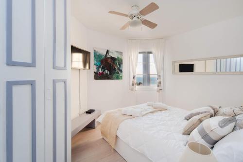 a white bedroom with a bed and a ceiling fan at Chic 3BR Apt w Parking on the Beach by Sea N' Rent in Tel Aviv