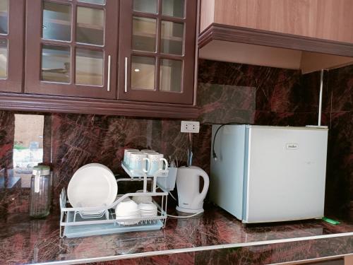 a kitchen counter with white dishes and a refrigerator at Raymundo Residence in Dumaguete