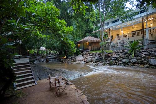 a river in front of a building with a waterfall at เดอะริเวอร์ แม่กำปอง The River Maekampong Chiang Mai in Ban Pok Nai