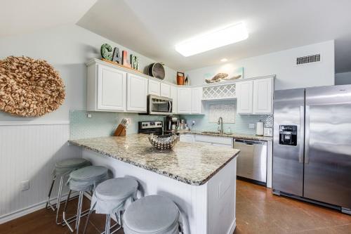 a kitchen with white cabinets and a counter with stools at Pirates Bay #118 The LUV Shack poolfront townhome in Port Aransas