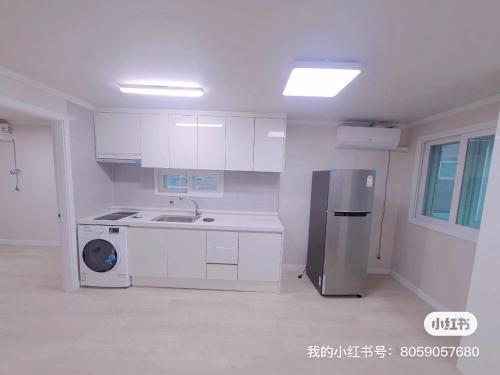eine weiße Küche mit einer Spüle und einem Kühlschrank in der Unterkunft A-one in Seoul