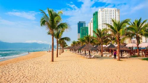 una playa con palmeras y edificios y el océano en The Dream Suite, en Da Nang