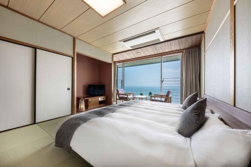 a bedroom with a large bed with a view of the ocean at Spa and Resort Hotel Solage Oita Hiji Beppuwan in Beppu
