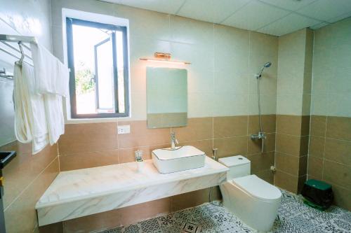 ein Badezimmer mit einem Waschbecken, einem WC und einem Spiegel in der Unterkunft BAO AN RESORT & BUNGALOW in Hòa Bình
