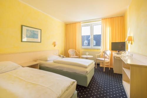 a hotel room with two beds and a television at Trip Inn Hotel Astoria in Göttingen