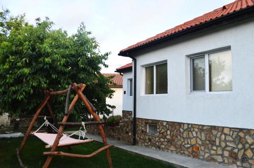 a swing in a yard next to a house at Guest House Sunrise in Shabla