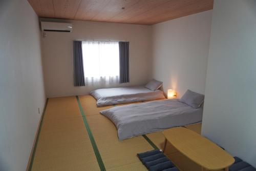 a room with two beds and a table and a window at 中崎町駅3分/梅田徒歩圏 100㎡ 3階建独棟町屋まるまる貸切 /梅田/大阪駅 in Osaka