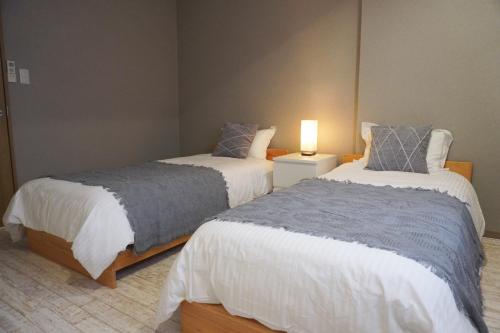 a bedroom with two beds and a lamp in it at 中崎町駅3分/梅田徒歩圏 100㎡ 3階建独棟町屋まるまる貸切 /梅田/大阪駅 in Osaka