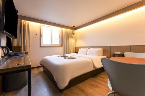 a hotel room with a large bed and a table at STAY201 in Jecheon
