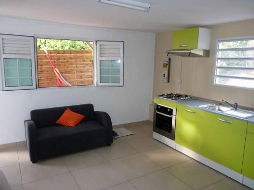a kitchen with a couch and a sink and a stove at Logement dans un lieu calme et verdoyant à proximité de tout avec Jacuzzi!!! in Basse-Terre