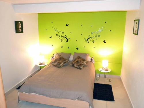 a bedroom with a bed with a green wall with butterflies at Logement dans un lieu calme et verdoyant à proximité de tout avec Jacuzzi!!! in Basse-Terre