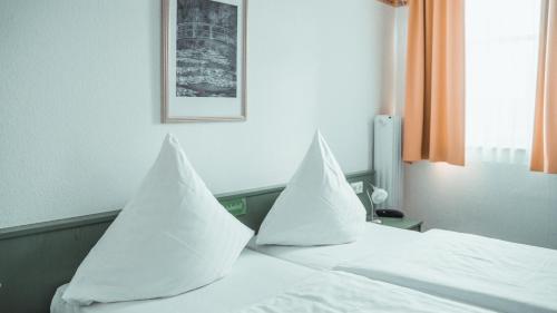 a bedroom with two white pillows on a bed at City Hotel in Delmenhorst