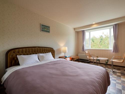 una camera con un grande letto e una finestra di Asama Kogen Hotel a Tsumagoi