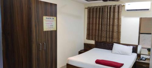 ムンバイにあるHansh Residencyのベッド1台と木製キャビネット付きの小さな客室です。