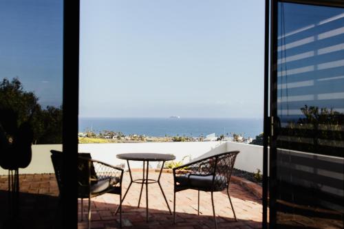 een patio met een tafel en stoelen en uitzicht op de oceaan bij San Miguel Hills in Ensenada