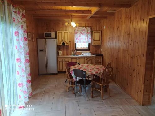 a kitchen with a table and chairs and a refrigerator at EkoZagroda in Skrzyneczki