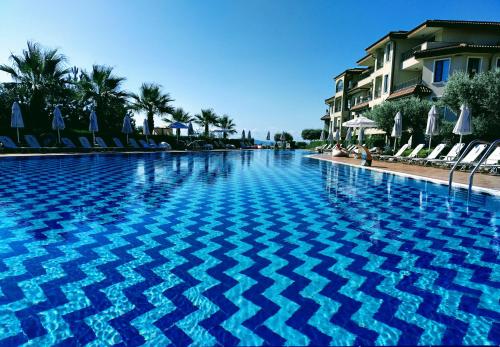 a blue swimming pool with chairs and a building at Apartment Melody in Burgas City