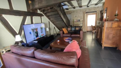 ein Wohnzimmer mit Ledersofas und einem TV in der Unterkunft Maison Barossa Issigeac in Issigeac