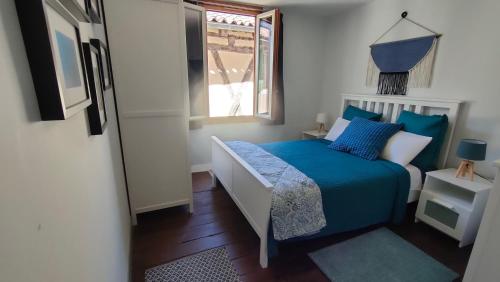 Schlafzimmer mit einem Bett mit blauer Bettwäsche und einem Fenster in der Unterkunft Maison Barossa Issigeac in Issigeac