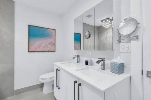 a white bathroom with a sink and a toilet at Luxury Designer Delray Beach. 10 Min to the Beach! in Delray Beach